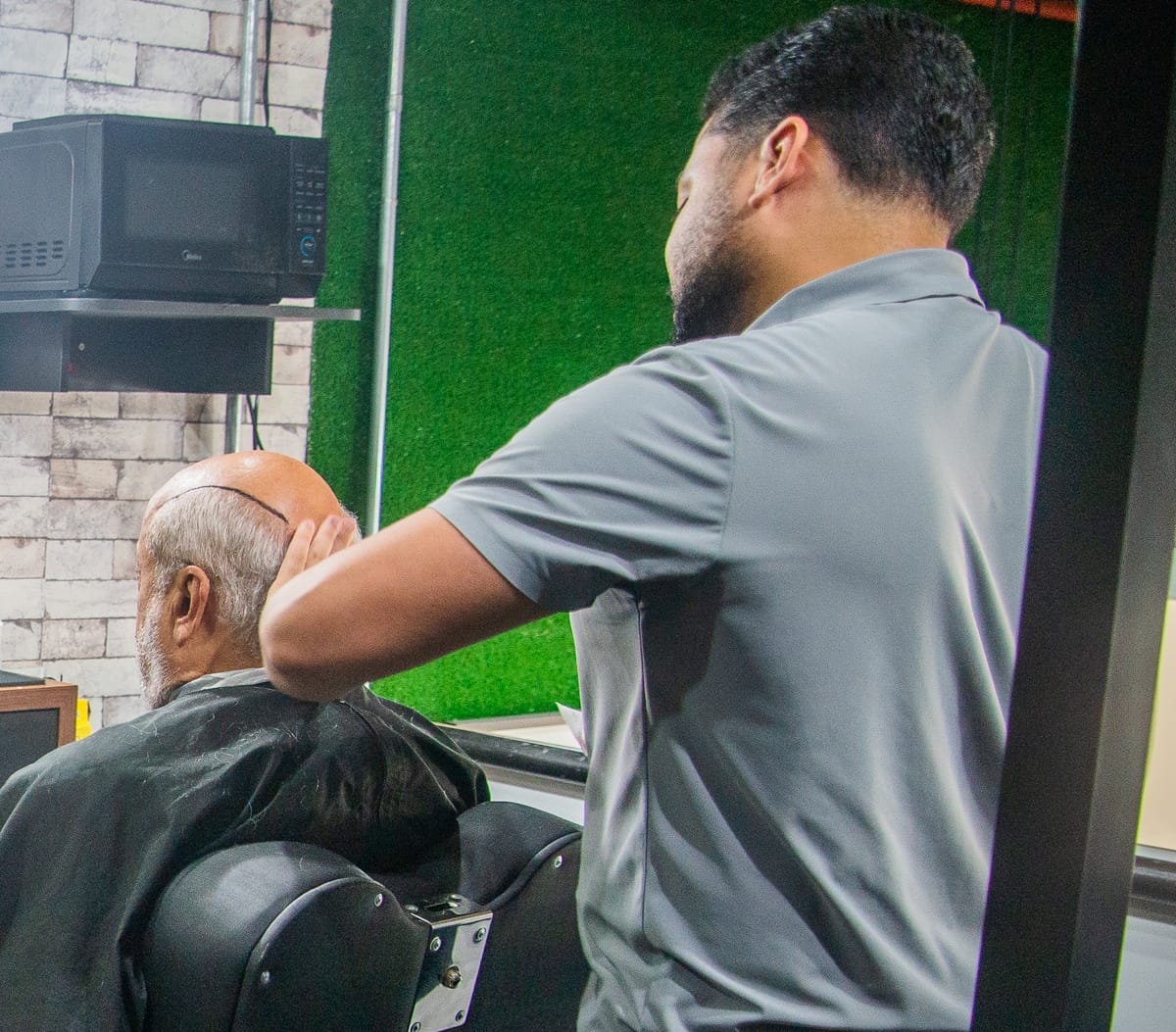 Barbeiro da Barba FC posicionando a área demarcada para prótese capilar, no São Rafael