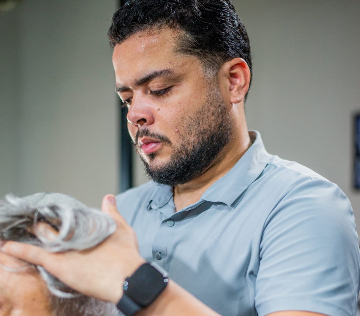 Barbeiro da Barba FC posicionando a prótese capilar de um cliente