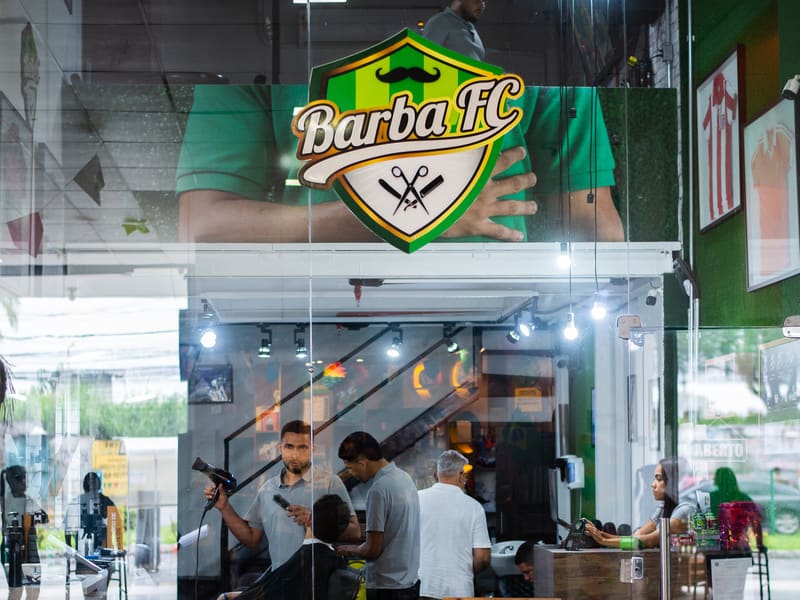 Vitrine de vidro da Barba FC com o escudo do clube e a equipe atendendo lá dentro
